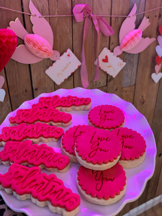 Handmade Valentine’s iced biscuits with pink icing and love message designs